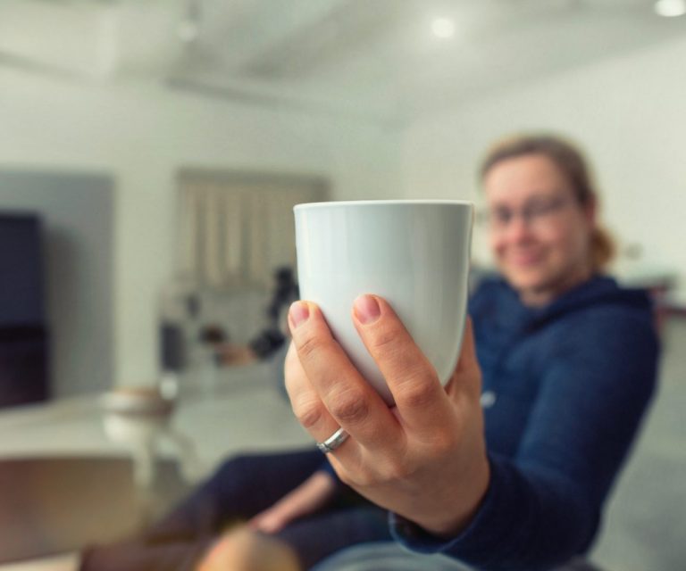 Katrin Zinke hält dem User einladend eine Tasse Kaffee entgegen.